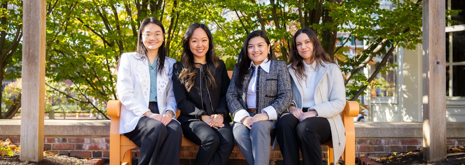 Four women on a bench smiling